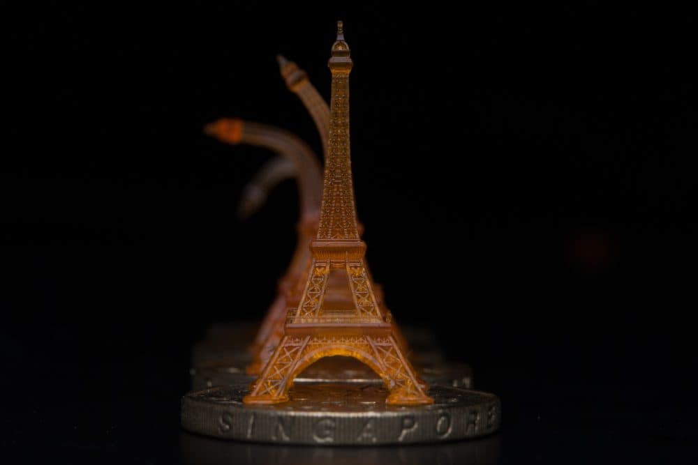 A shape memory Eiffel tower was 3-D printed using projection microstereolithography. Here you can see it recovering from being bent after toughening on a heated Singapore dollar coin. (Courtesy of Qi (Kevin) Ge/MIT)