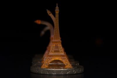 A shape memory Eiffel tower was 3-D printed using projection microstereolithography. Here you can see it recovering from being bent after toughening on a heated Singapore dollar coin. (Courtesy of Qi (Kevin) Ge/MIT)