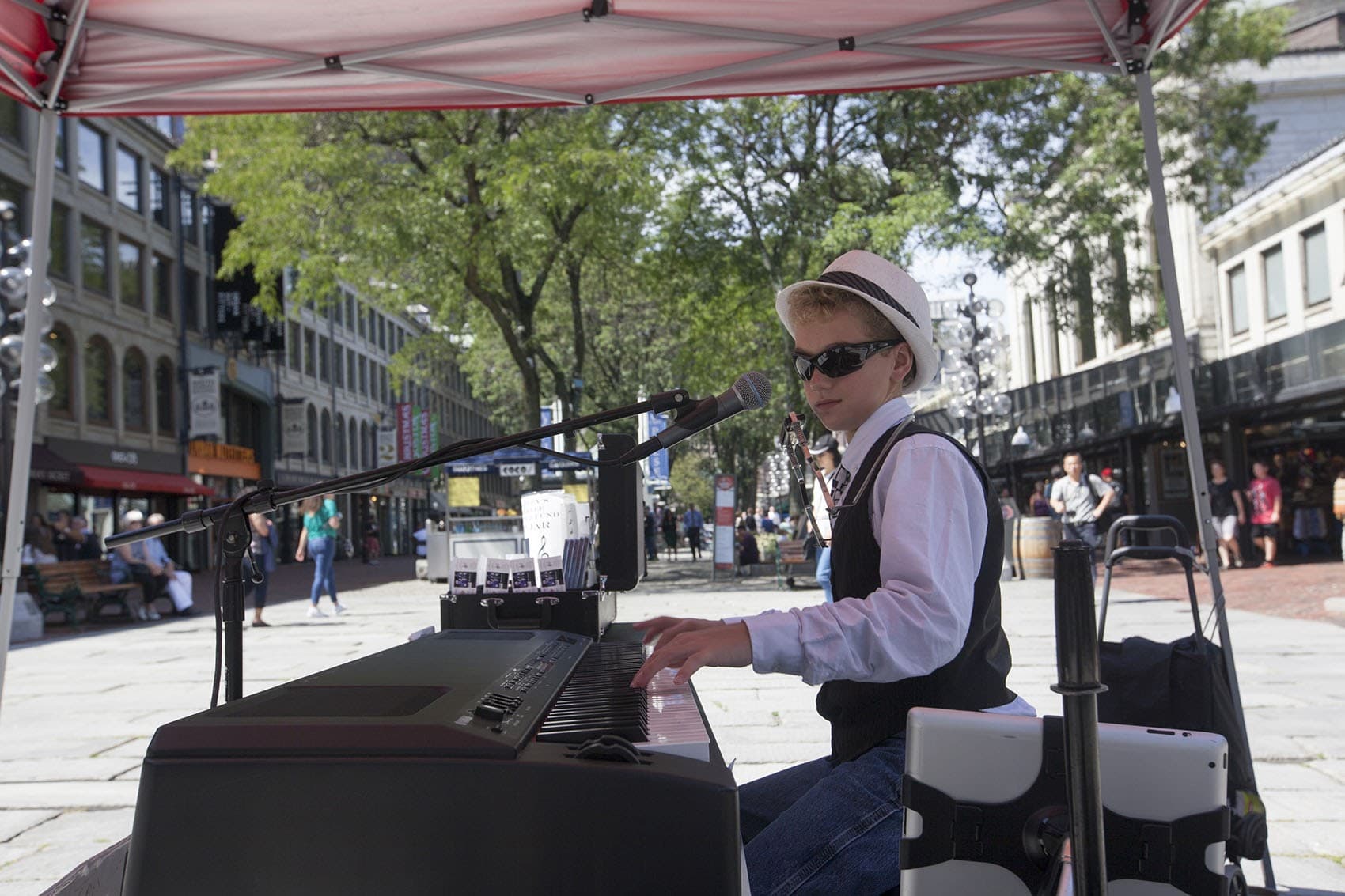 Bradley Bartlett-Roche, known as the Boston Piano Kid, plays in Faneuil Hall this summer. (Joe Difazio for WBUR)