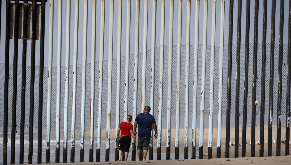Two people walk towards metal bars marking the United States border where it meets the Pacific Ocean Wednesday, March 2, 2016, in Tijuana, Mexico. (Gregory Bull/AP)