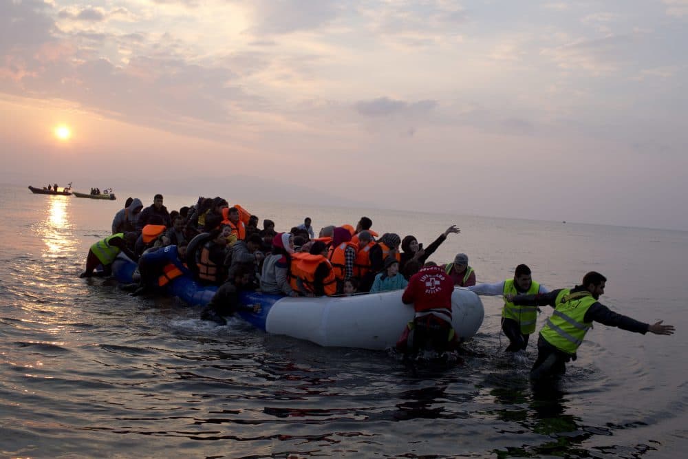 Volunteers help migrants and refugees on a dingy as they arrive at the shore of the northeastern Greek island of Lesbos, after crossing the Aegean sea from Turkey. (Petros Giannakouris/AP)