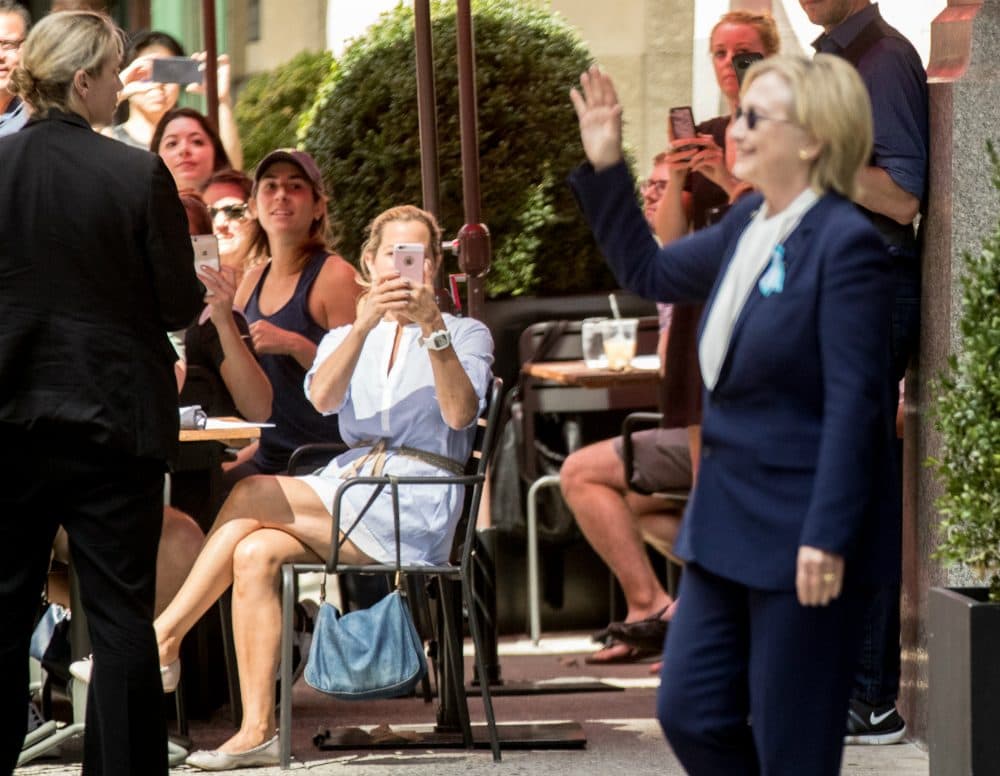 People on the street photograph Democratic presidential candidate Hillary Clinton as she leaves an apartment building Sunday, Sept. 11, 2016, in New York. (Andrew Harnik/AP)