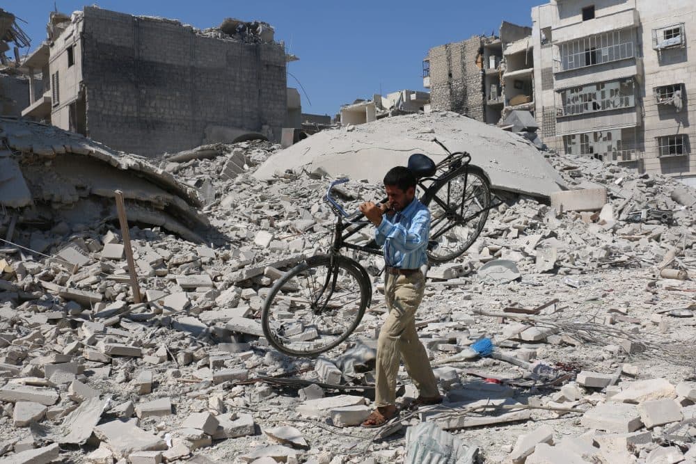 A Syrian man carrying a bicycle makes his way through the rubble of destroyed buildings following a reported air strike on the rebel-held Salihin neighbourhood of the northern city of Aleppo, on Sept. 11, 2016. (Ameer Alhabi/AFP/Getty Images)