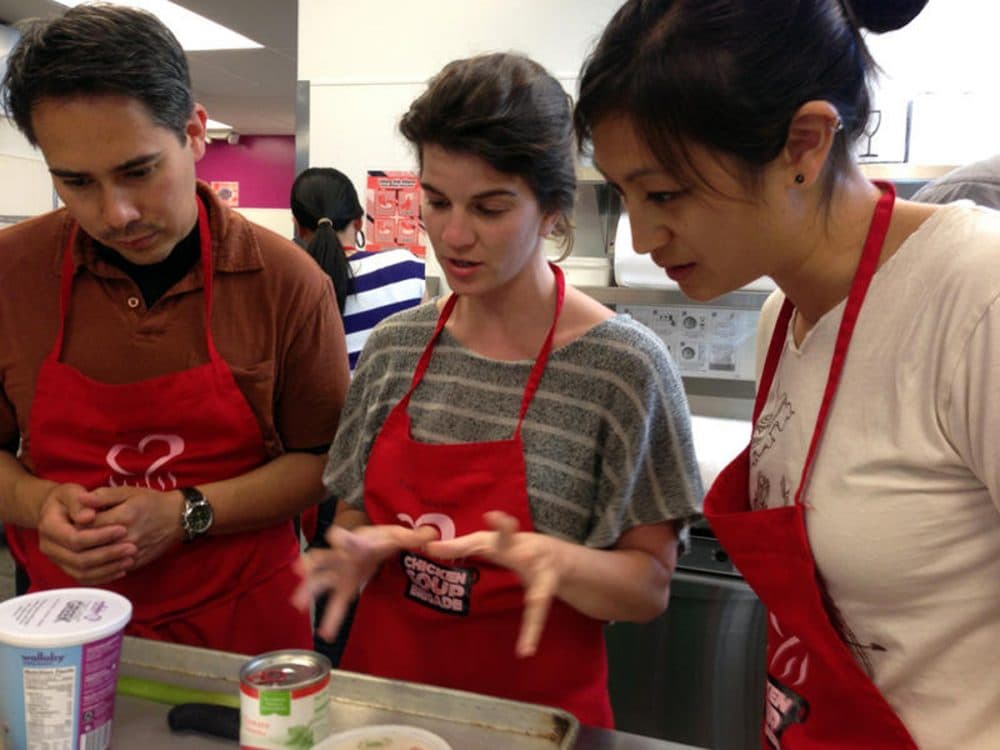Medical residents Bryn Chowchuvech, Bari Laskow and Tiffany Ho discuss strategy for making their spaghetti dish. (Ruby de Luna/KUOW)
