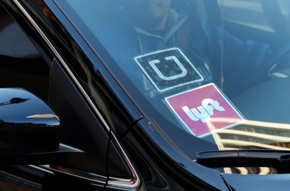 A driver displaying Lyft and Uber stickers on his front windshield. (Richard Vogel/AP)
