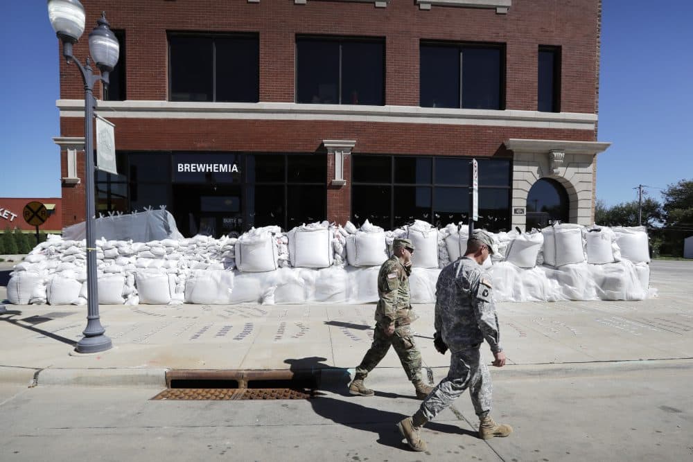 Iowa National Guard members walk past a local business covered in sandbags, Monday, Sept. 26, 2016, in Cedar Rapids, Iowa. (Charlie Neibergall/AP)