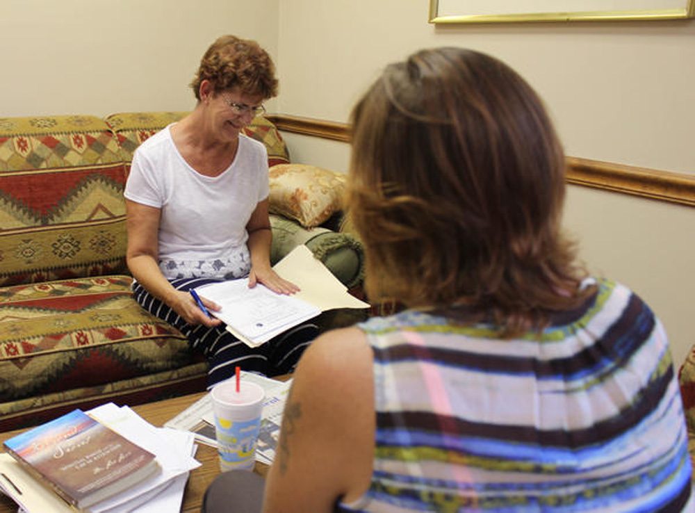 Peer support sepcialist Sally Moore (left) gives a needs assessment to Deana Kilpatrick at PEEPs in Recovery in Reeds Spring, Mo. (Bram Sable-Smith/KBIA/Side Effects Public Media)