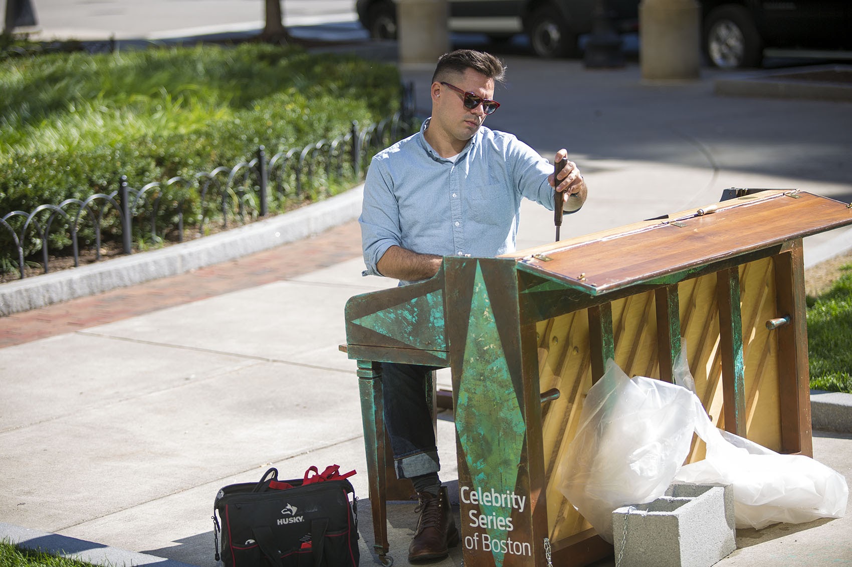 Piano technician Michael Wilson tunes one of the &quot;Play Me, I'm Yours&quot; pianos, this one in Statler Park near the Park Plaza Hotel in Boston. (Jesse Costa/WBUR)