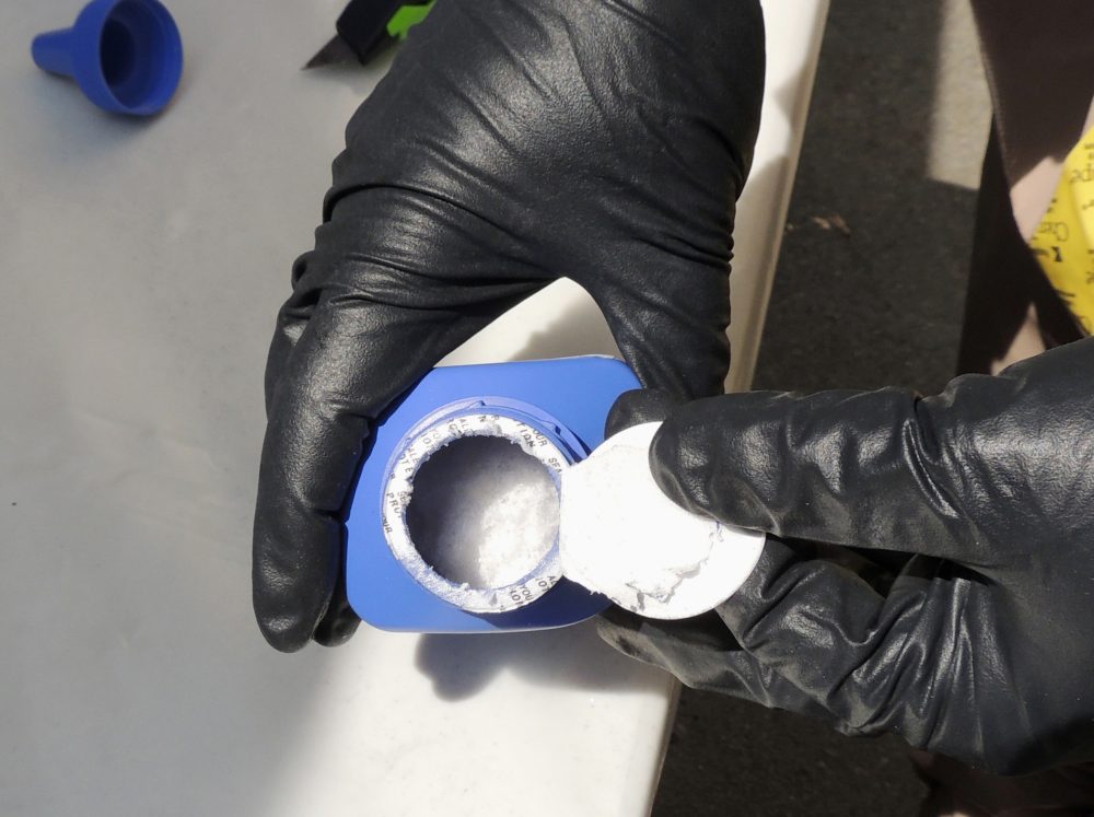 In this photo provided by the Royal Canadian Mounted Police, a member of the RCMP opens a printer ink bottle containing the opioid carfentanil imported from China, in Vancouver. (Royal Canadian Mounted Police via AP)