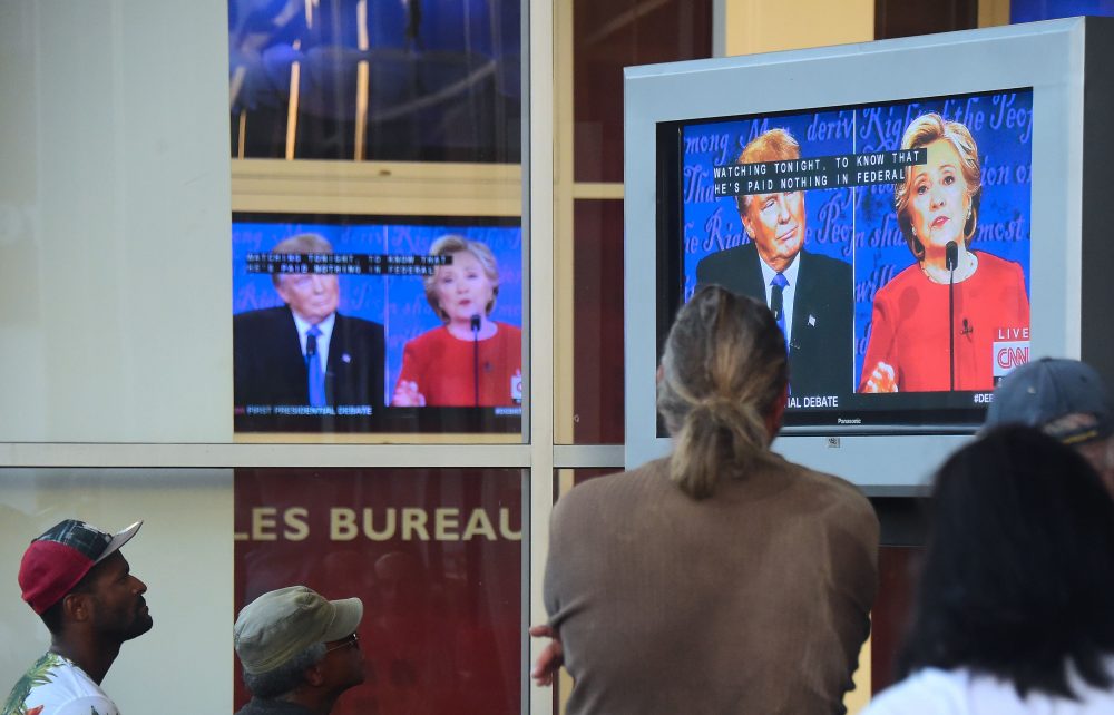 People gather to watch the first U.S. presidential debate between Hillary Clinton and Donald Trump, nominees for the Democratic and Republican parties respectively, on a television set in front of an office building in Hollywood, Calif., on Sept. 26, 2016. (Frederic J Brown/AFP/Getty Images)