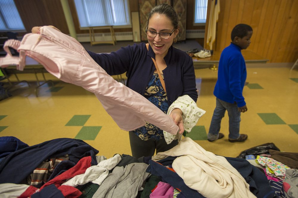 Tiana Guerra of Cuba is expecting to have a baby girl in about a month. She came to the clothing drive at First United Baptist Church to look for baby clothes and gets excited as she pulls out a pair of pink winter pants. (Jesse Costa/WBUR)