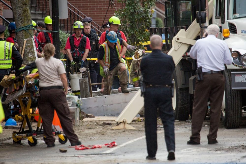 Boston firefighters work to retrieve the two men who were killed as a result of the water main break on Dartmouth Street on Friday. (Jesse Costa/WBUR)