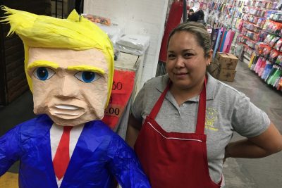 Alma Cruz shows off a Donald Trump piñata that’s for sale at a party store in Nogales, Mexico. She says a customer in the District of Columbia has ordered several of them. (Valeria Fernandez for Here & Now)