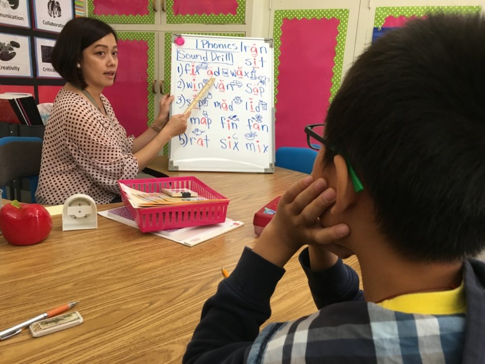 San Gabriel teacher Jenny Tan helps a student who's been in the U.S. less than a year learn the basics of English. (Adolfo Guzman-Lopez/KPCC)