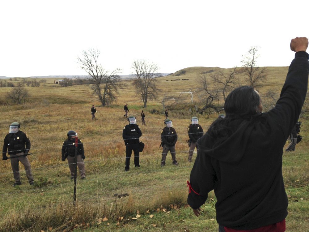 A Dakota Access pipeline protester defies law enforcement officers who are trying to force them from a camp on private land in the path of pipeline construction, Thursday, Oct. 27, 2016 near Cannon Ball, N.D. (James MacPherson/AP Photo)