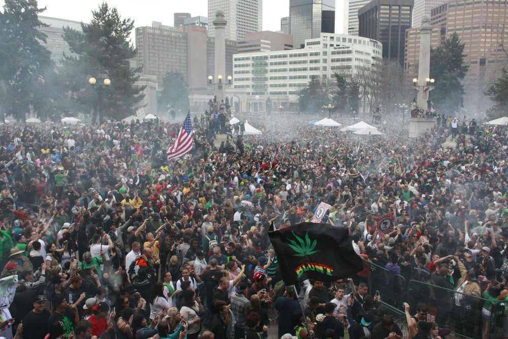 Let other states contend with the frenzied embrace of the new law, writes Susan E. Reed. Massachusetts can legalize marijuana after the party is over. Pictured: Members of a crowd numbering tens of thousands smoke marijuana at the Denver 4/20 pro-marijuana rally at Civic Center Park in Denver in 2013. (Brennan Linsley/AP)