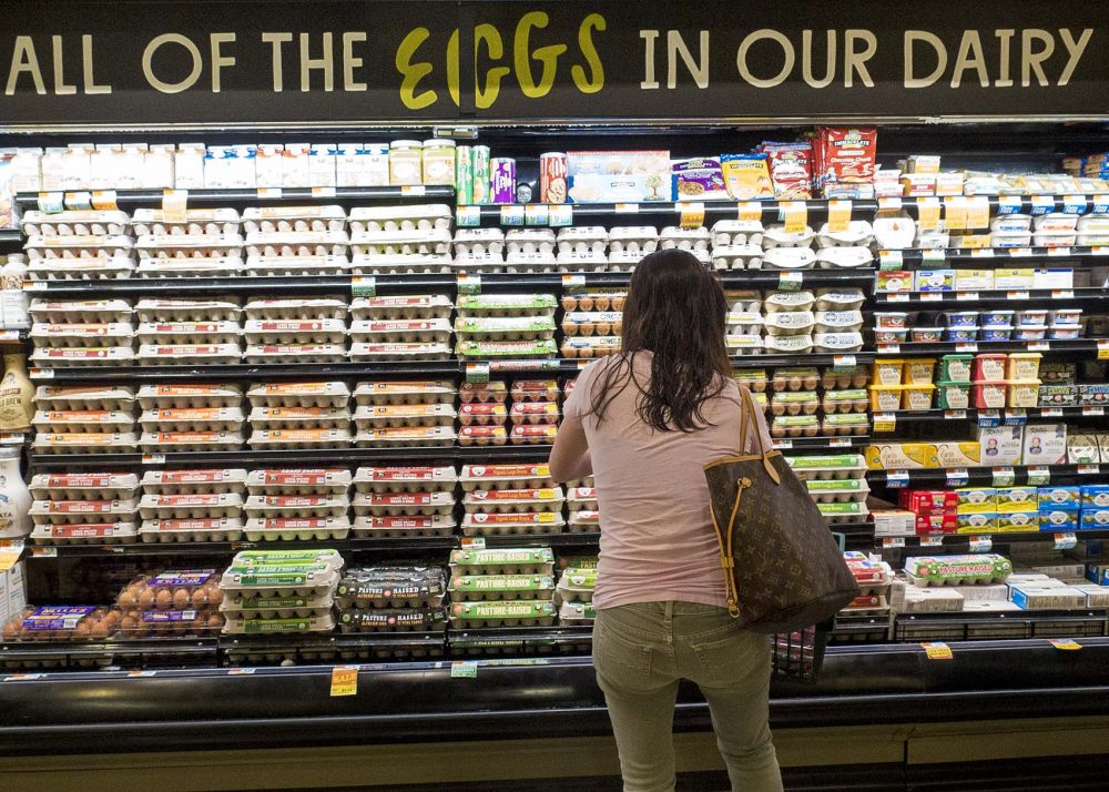 A consumer looks over Whole Foods Market's extensive selection of eggs that already comply with Question 3 requirements. (Andrea Shea/WBUR)