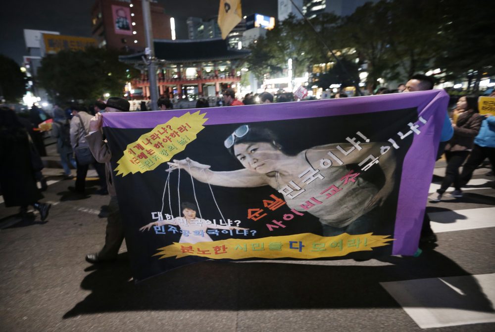 South Korean protesters carry a banner depicting South Korean President Park Geun-hye, left bottom, as a marionette and Choi Soon-sil, who is at the center of a political scandal, as a puppeteer after a rally calling for Park to step down to step down in downtown Seoul, South Korea, Monday, Oct. 31, 2016. A scandal exploded last week when Park acknowledged that Choi, a cult leader's daughter with a decades-long connection to Park, had edited some of her speeches and provided public relations help. The letters read &quot;Park Geun-hye should step down.&quot; (Ahn Young-joon/AP)