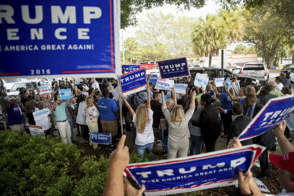 Supporters of Republican presidential candidate Donald Trump wave signs as Democratic presidential candidate Hillary Clinton greets supporters outside an early voting station in Pompano Beach, Fla., Sunday, Oct. 30, 2016. (Andrew Harnik/AP)