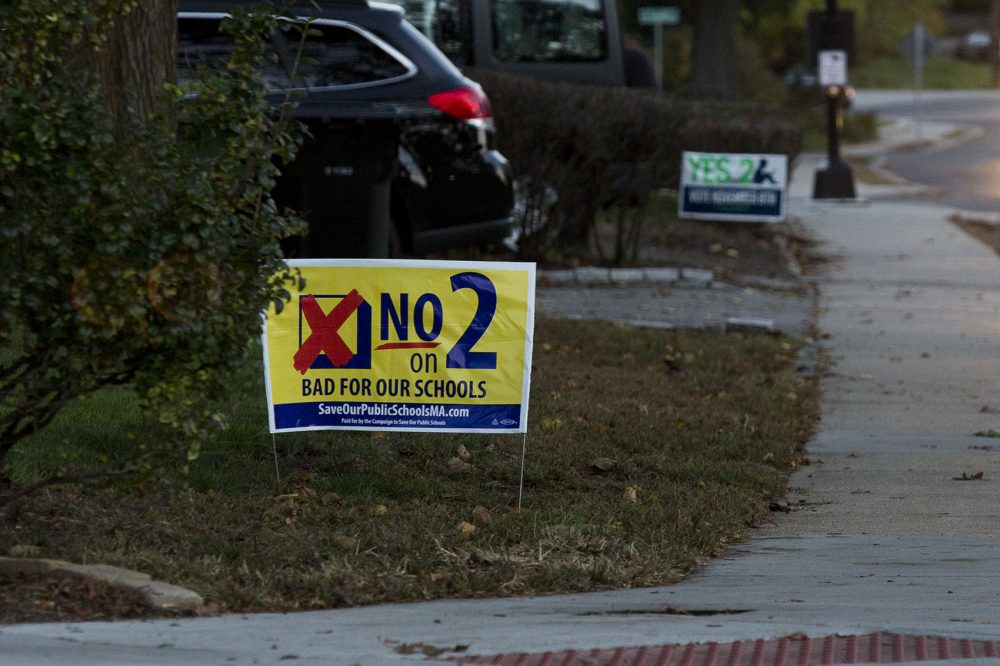 Next-door neighbors on Orchard Street in Watertown show their opinions about Question 2, one sign supporting the expansion of charter schools and one sign opposing it. (Jesse Costa/WBUR)