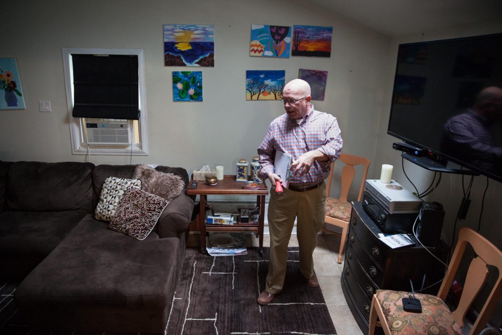 Ken Aligata walks through an inspection of Right Path House in Clinton, Conn. Artwork made by residents during therapy sessions hangs on the wall behind him. (Ryan Caron King/WNPR)