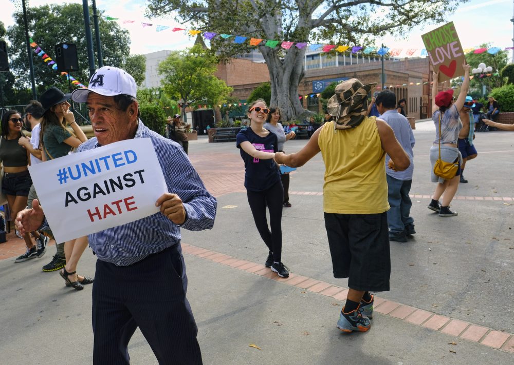 A man carrying a sign that reads &quot;United Against Hate&quot; dances with other demonstrators during a demonstration against presidential elect Donald Trump in Oliveira Plaza in downtown Los Angeles on Saturday, Nov. 12, 2016. (Richard Vogel/AP)