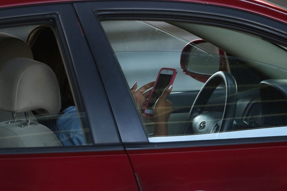 A driver uses a phone while behind the wheel of a car in New York in April 2016. (Spencer Platt/Getty Images)