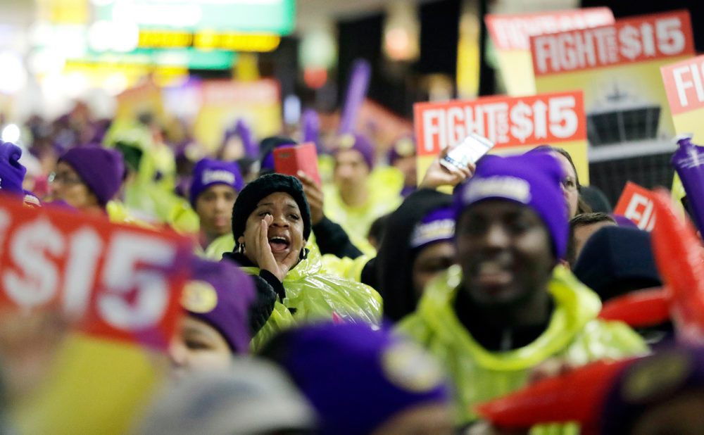 A woman shouts while marching with service workers asking for $15 minimum wage pay during a rally at Newark Liberty International Airport on Tuesday. (Julio Cortez/AP)