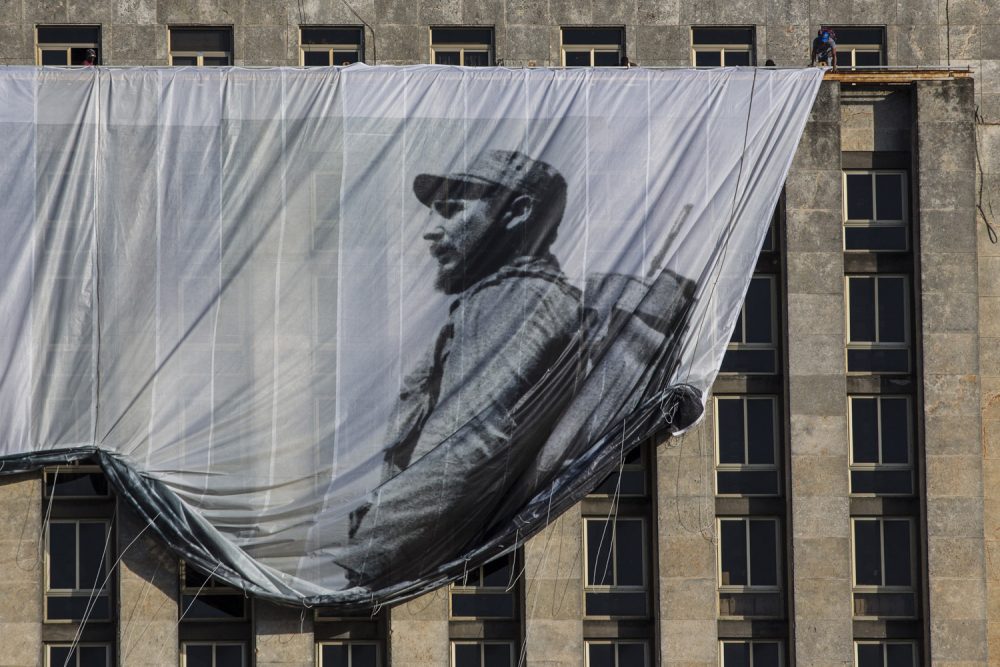 Men hang a giant banner with a picture of Cuba's late leader Fidel Castro as a young revolutionary, from the Cuban National Library building in Havana, Cuba. (Desmond Boylan/AP)