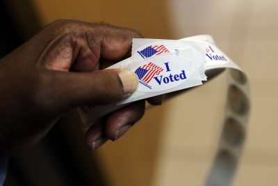 A volunteer prepares to hand out stickers to voters at an early polling station in Towson, Md. (Patrick Semansky/AP)