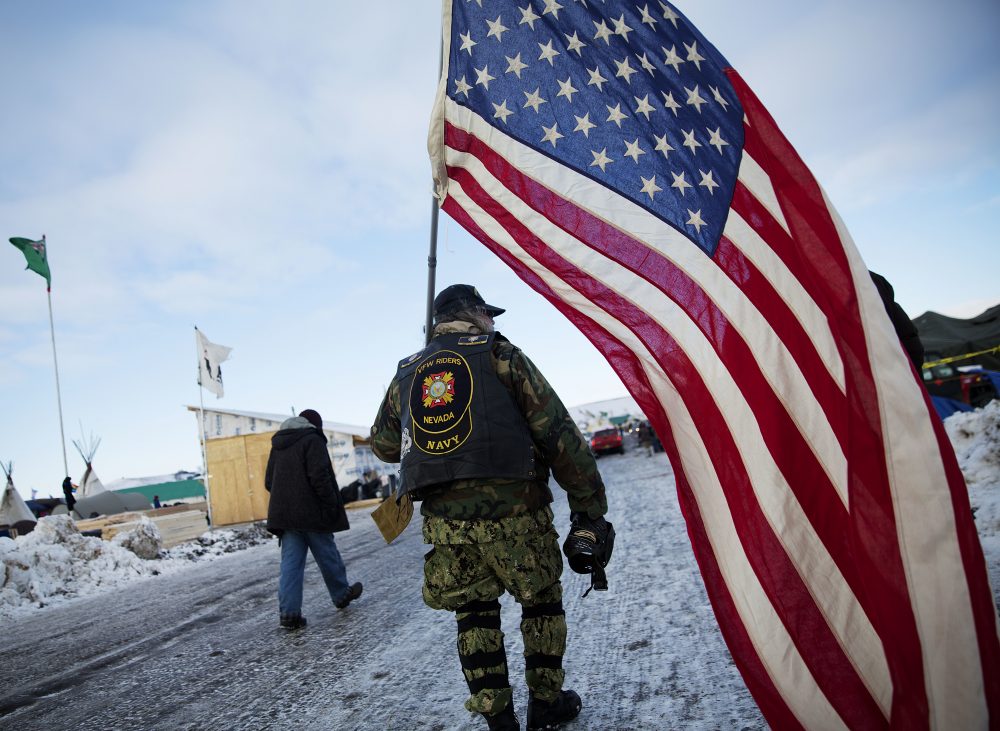 Navy veteran Rob McHaney, of Reno, N.V., walks with an American flag at the Oceti Sakowin camp where people have gathered to protest the Dakota Access oil pipeline in Cannon Ball, N.D., Sunday, Dec. 4, 2016. (David Goldman/AP)