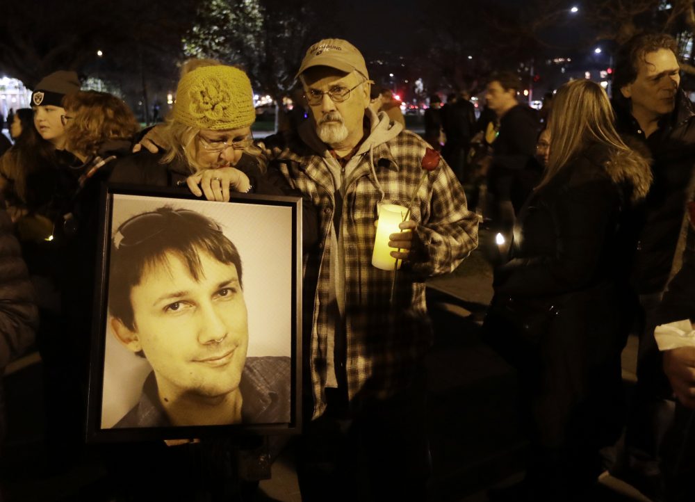 Judy Hough, left, and her husband Brian, center, hold a picture of their son Travis, who died in a warehouse fire, during a vigil at Lake Merritt on Monday, Dec. 5, 2016, in Oakland, Calif. (Marcio Jose Sanchez/AP)