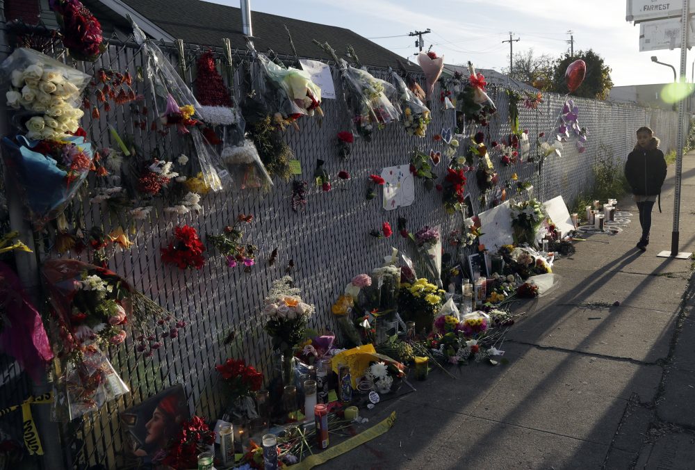 Flowers, pictures and candles adorn a fence at a makeshift memorial near the site of the warehouse fire in Oakland, California. (Marcio Jose Sanchez/AP)
