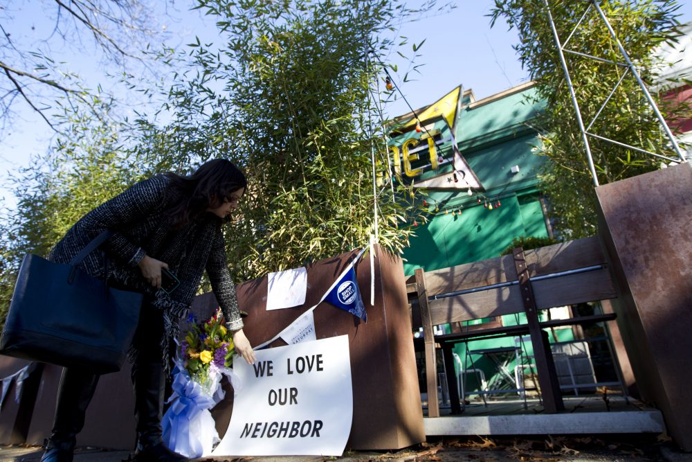 Meighan Stone places a support banner with flowers outside the door of Comet Ping Pong pizza shop, in Washington, Monday, Dec. 5, 2016. A fake news story prompted a man to fire a rifle inside the popular Washington, D.C., pizza place as he attempted to &quot;self-investigate&quot; a conspiracy theory that Hillary Clinton was running a child sex ring from there, police said. (Jose Luis Magana/AP)