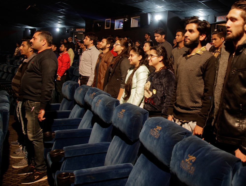 Indian moviegoers stand up as national anthem is played at a movie hall before the screening of a movie in Jammu, India, Tuesday, Dec. 13, 2016. A ruling by India's Supreme Court in November said that the anthem must be played before every film screening in the country and that audiences must stand. The court said the rule was aimed at instilling a sense of patriotism. (Channi Anand/AP)