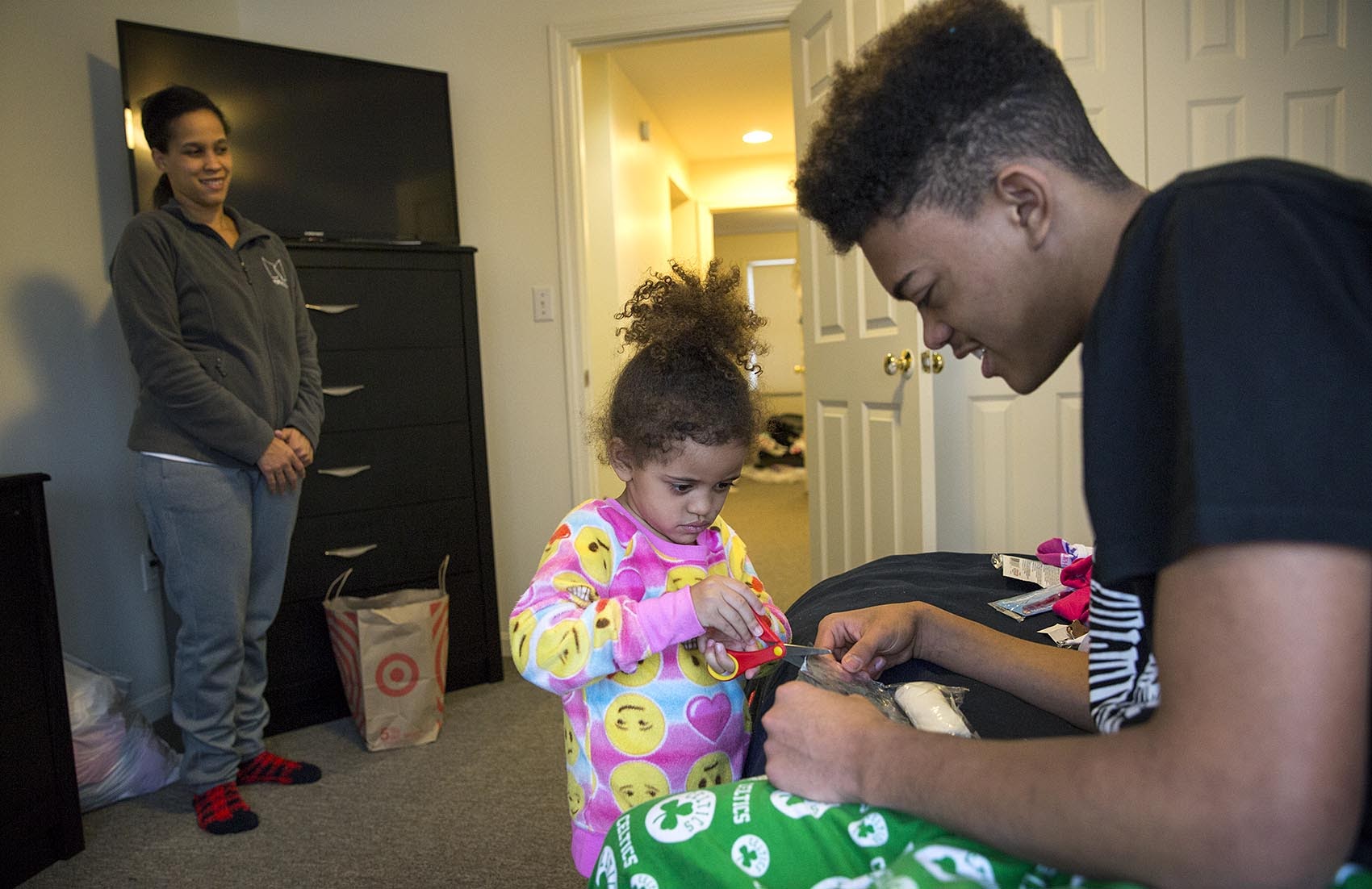Settling into their new home, Isaiah Robinson, 16, plays with his sister Juliah, 3, as their mother, Heather, looks on. (Robin Lubbock/WBUR)