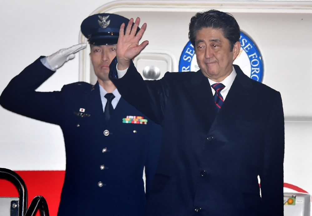 Japan's Prime Minister Shinzo Abe (right) waves before departure for Hawaii at Tokyo's Haneda airport on Dec. 26, 2016. (Kazuhiro Nogi/AFP/Getty Images)
