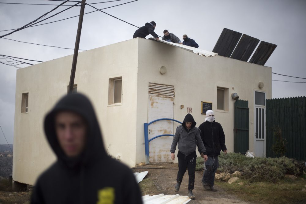 Jewish settler youth prepare barricades to block the entrance to a building in Amona, an unauthorized Israeli outpost in the West Bank, east of the Palestinian town of Ramallah, Thursday, Dec. 15, 2016. (Ariel Schalit/AP)