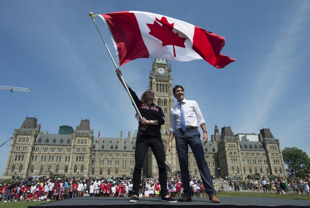 Canadian Prime Minister Justin Trudeau looks on as athlete Rosie MacLennan waves the Maple Leaf after being named as the flag bearer for the Summer Olympics, on July 21 in Ottawa. (Adrian Wyld/The Canadian Press via AP)