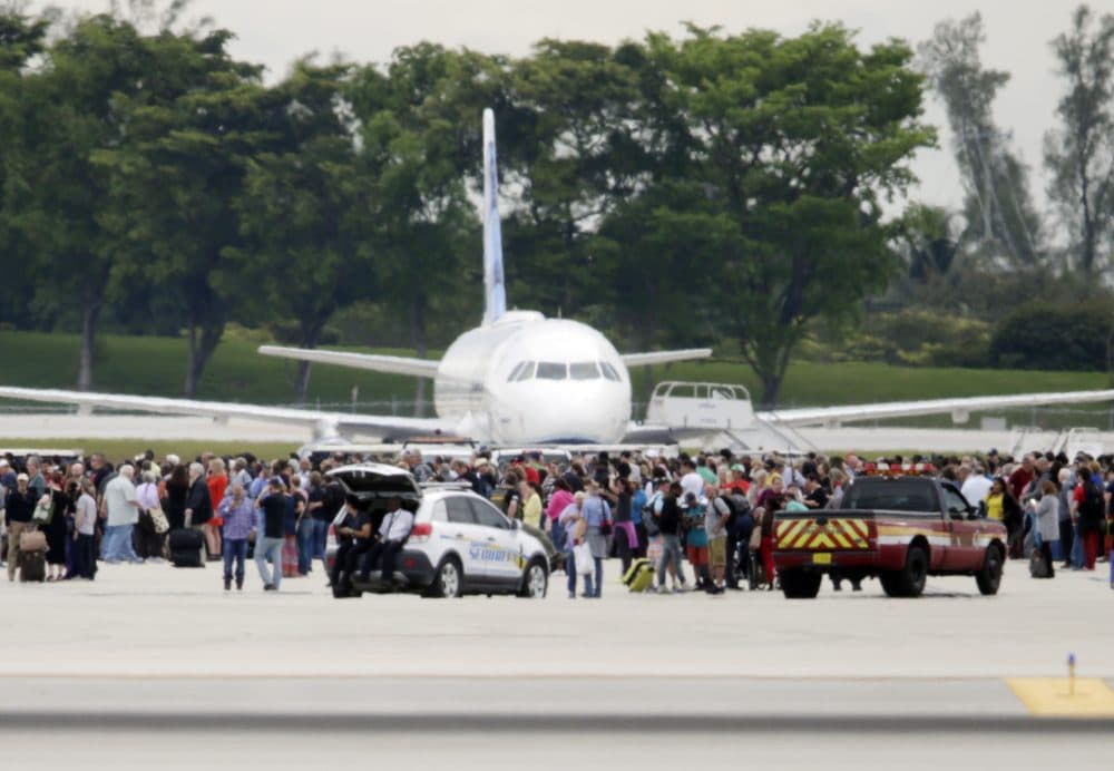 People stand on the tarmac at the Fort Lauderdale-Hollywood International Airport after a shooter opened fire inside a terminal of the airport, killing several people and wounding others before being taken into custody, Friday, Jan. 6, 2017, in Fort Lauderdale, Fla. (Lynne Sladky/AP)