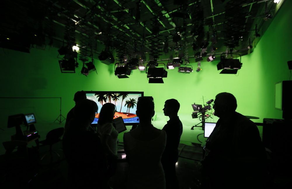 Employees of the state-owned English-language Russia Today (RT) television network are silhouetted against the backdrop at the RT new studio complex in Moscow in June 2013. (Yuri Kochetkov/AFP/Getty Images)