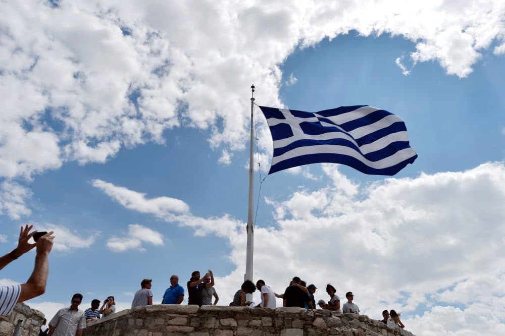 A man takes picture of a Greek flag atop the Acropolis archaeological site in August 2015. (Louisa Gouliamaki/AFP/Getty Images)
