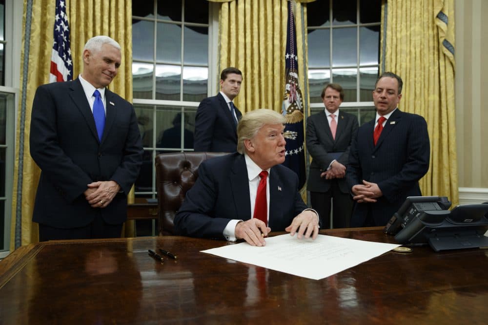 Vice President Mike Pence watches at left as President Donald Trump prepares to sign his first executive order, Friday, Jan. 20, 2017, in the Oval Office of the White House in Washington. (Evan Vucci/AP)