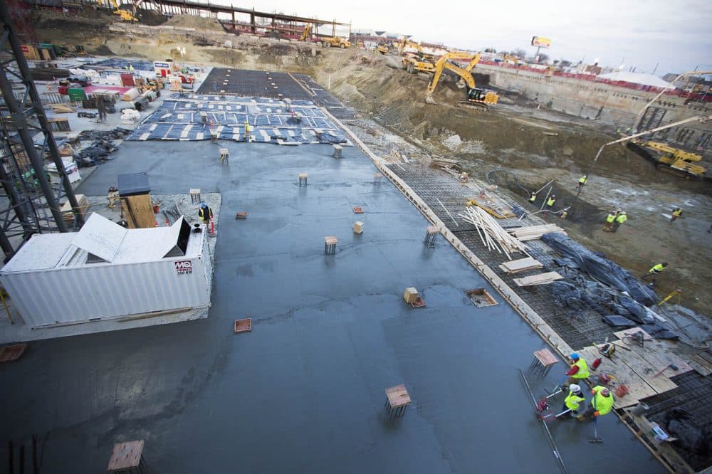 Workers smooth out freshly laid concrete for a basement parking lot of the Wynn Boston Harbor Casino in Everett. (Jesse Costa/WBUR)