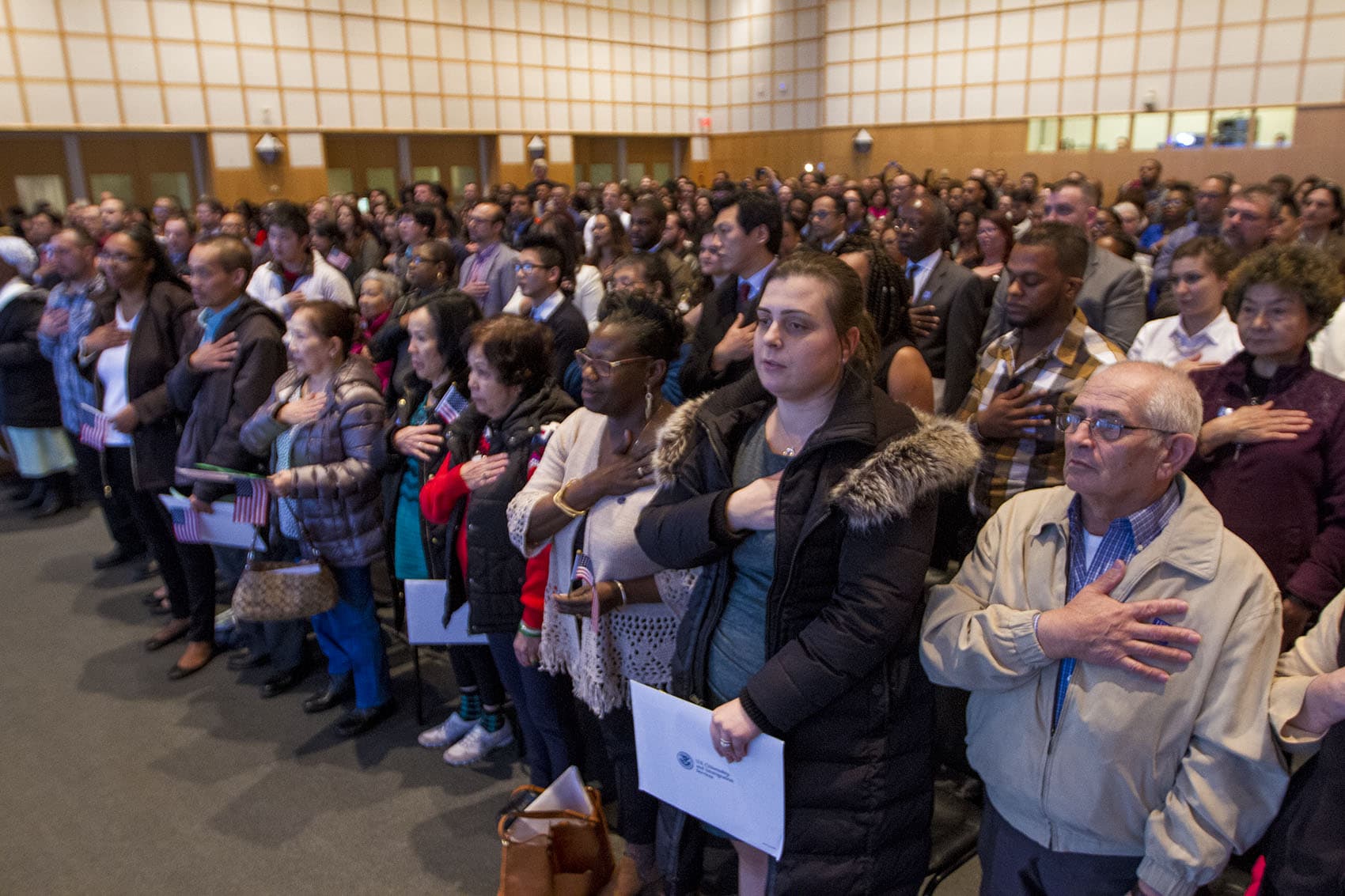 New citizens recite the Pledge Of Allegiance during a ceremony at the Boston's JFK Library on Thursday. (Jesse Costa/WBUR)