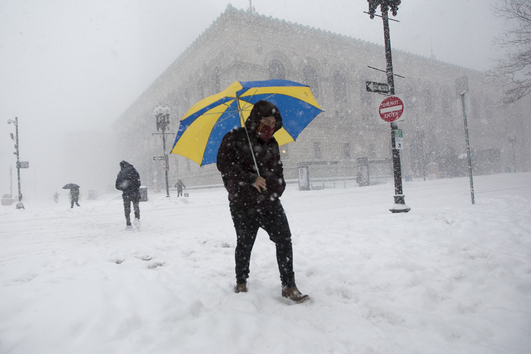 A man with an umbrella walks through Copley Square during the snowstorm. (Jesse Costa/WBUR)