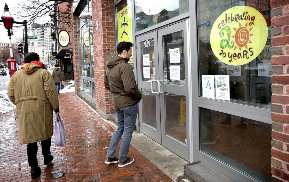 Jake Shuman, 23, reads a sign on the door of Anna's Taqueria on Cambridge Street in Boston. It says the restaurant is closed to support &quot;our employees desire to participate in the 'Day Without Immigrants.' &quot; (Robin Lubbock/WBUR)