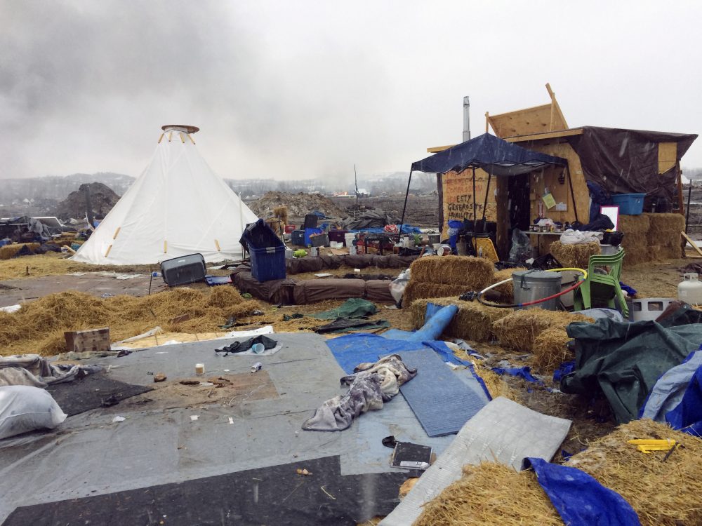 Refuse remains in the Dakota Access pipeline opponents' main protest camp as a fire burns in the background in southern North Dakota near Cannon Ball, N.D., on Wednesday, Feb. 22, 2017, as authorities prepare to shut down the camp in advance of spring flooding season. (Blake Nicholson/AP)