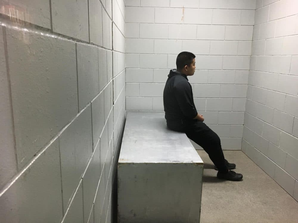 Raymond Haogun sits inside a replica of solitary confinement cell. (Lori Mack/WNPR)