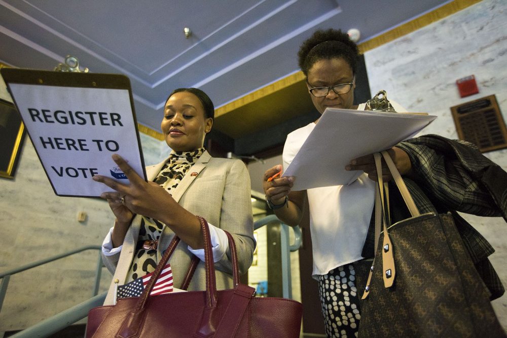 With a weakened Voting Rights Act and a new Trump Administration, the task of making it easier and fairer to vote falls to the states, writes Jamie Hoag. Pictured here: Emmy Shange from Tanzania (left) and Sandra Lebrun from Haiti register to vote immediately after the naturalization ceremony at Jenkins Auditorium at Malden High School. (WBUR)